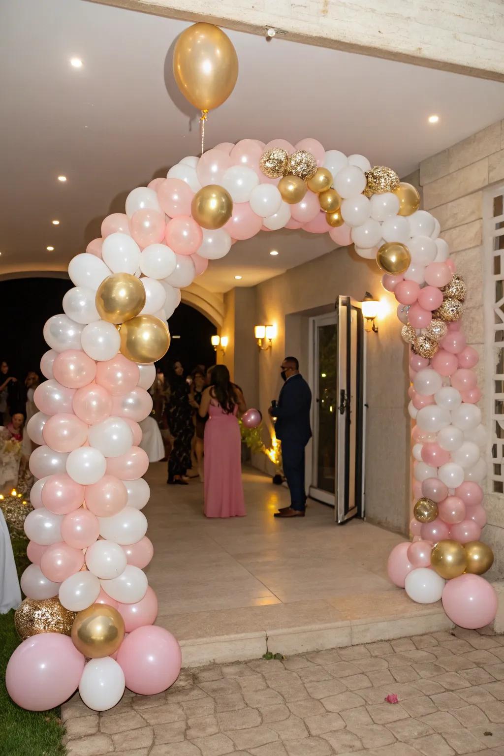 A striking balloon archway in pink, gold, and white extends a warm welcome to visitors.