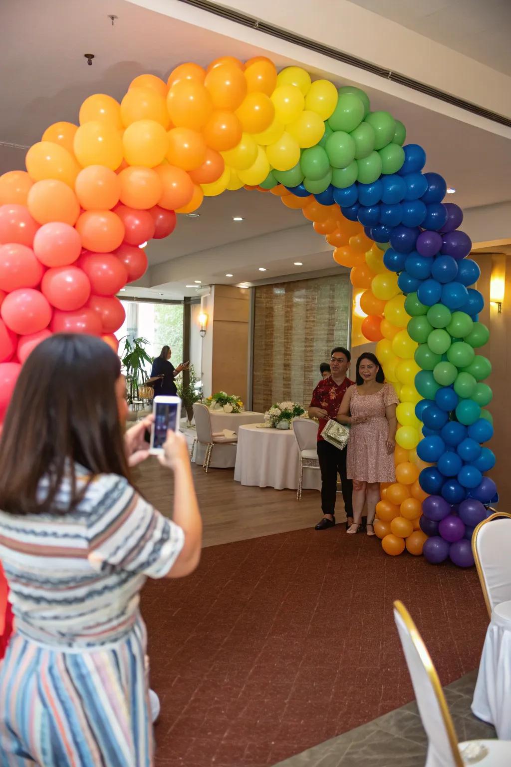 Attendees captivated by a striking spectrum balloon gateway at a party's entrance.
