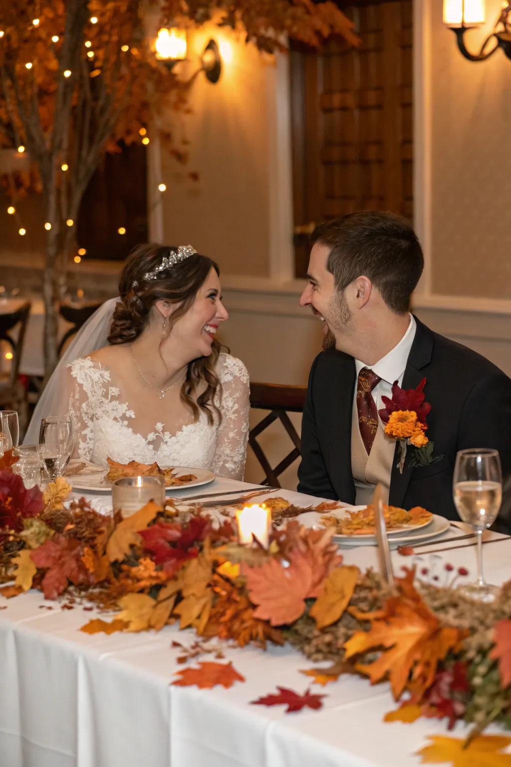 The bride and groom are seated at a table decorated with festive seasonal touches like autumnal leaves.